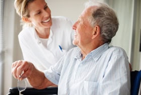 elderly man getting rehab with a nurse assisting and laughing with him