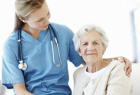 elderly woman in a nursing home next to a nurse wearing a stethoscope