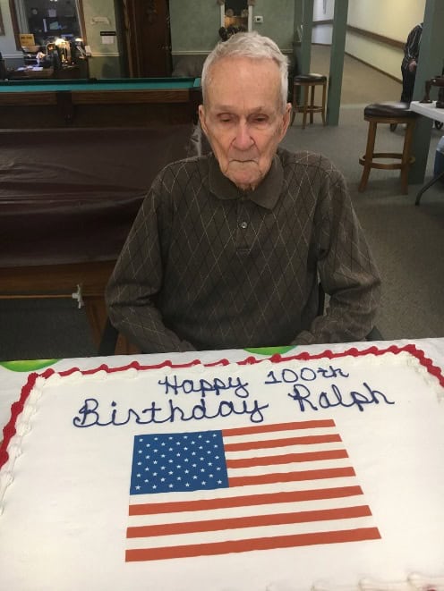 Photo of Ralph, a veteran and resident at Pleasant View Home, and a birthday cake with the American flag celebrating his 100th birthday at the nursing home.